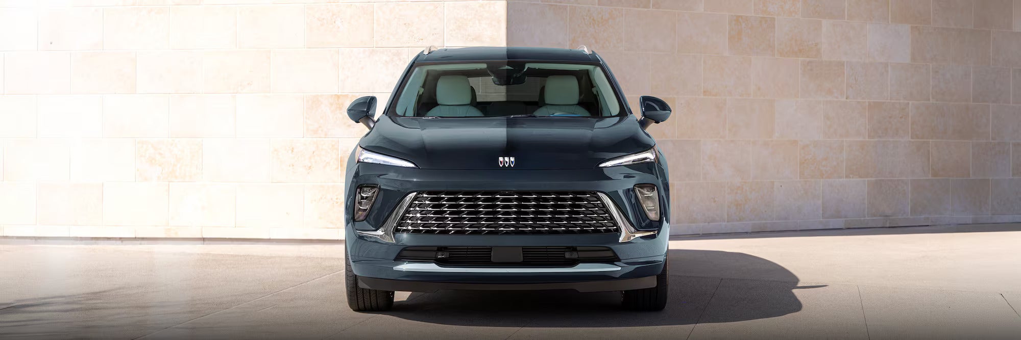 Front view of a dark blue Buick E5 electric SUV parked in front of a beige stone wall.